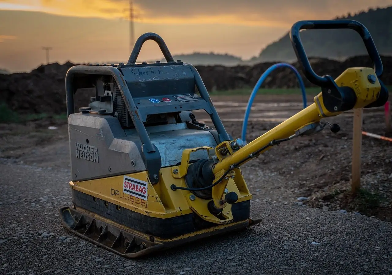Plate compactor on a dirt construction site at sunset